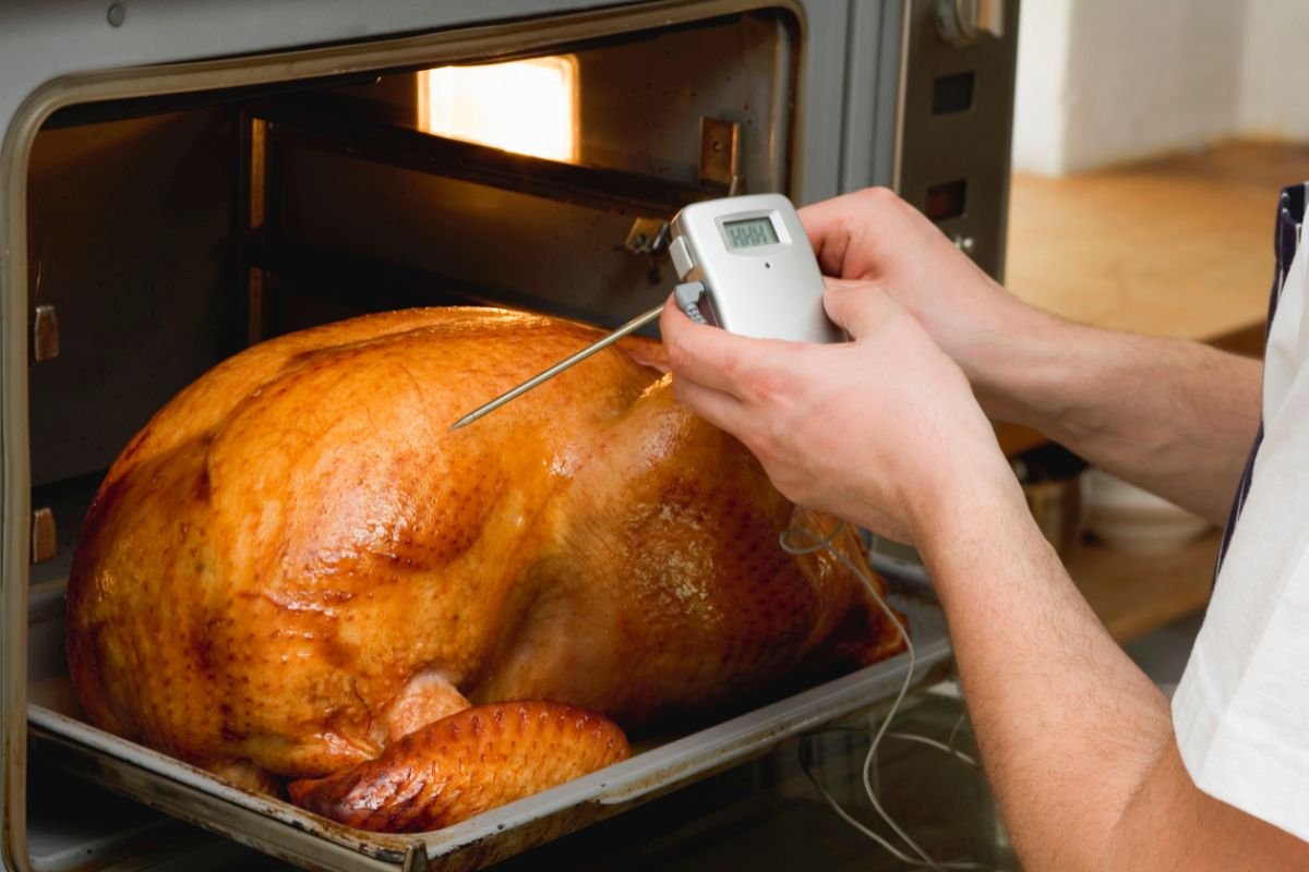 A grill chicken into the oven and a man using a Instant Read Thermometers